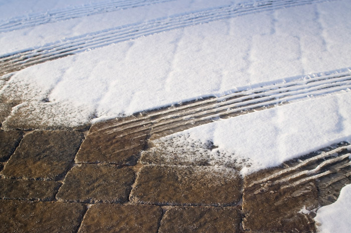 Close view of Belgard Commercial Mega-Bergerac Pavers with tire tracks in snow.